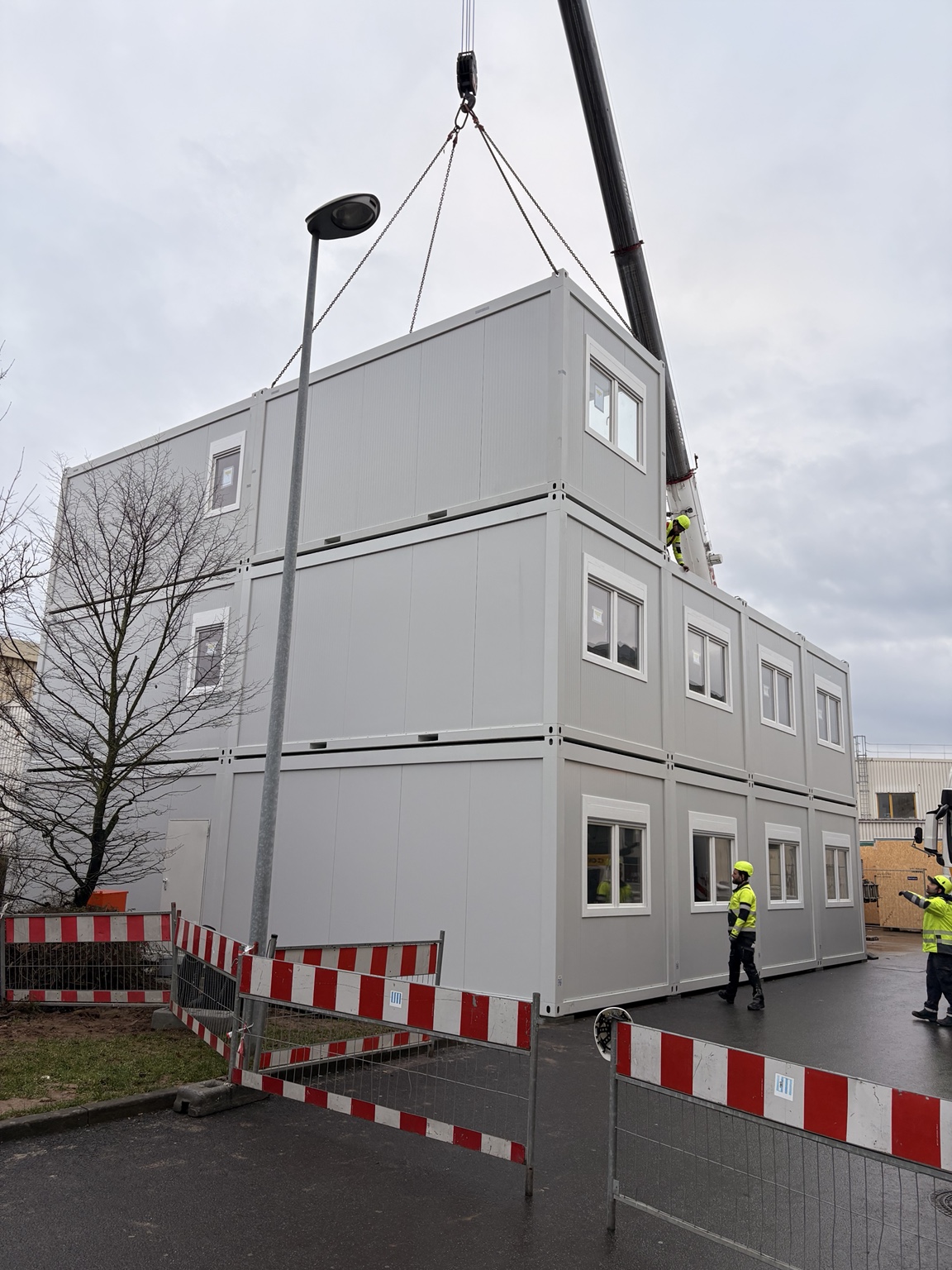 Kran setzt ein Containermodul auf eine mehrgeschossige Containeranlage